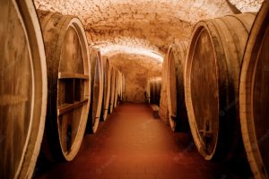 old-aged-traditional-wooden-barrels-with-wine-vault-lined-up-cool-dark-cellar-italy-porto-portugal-france_194143-1269
