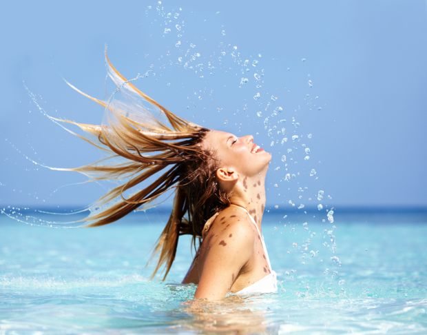 Attractive young woman playfully splashing in the ocean