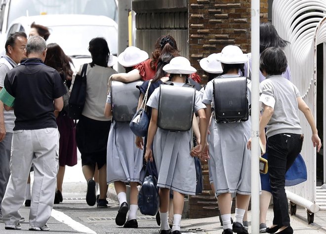 CARITAS Elementary School students leave their school with parents following an attack in Kawasaki, near Tokyo Tuesday, May 28, 2019.  A man carrying a knife in each hand and screaming "I will kill you" attacked schoolgirls waiting at a bus stop just outside Tokyo on Tuesday, Japanese authorities and media said. (Shinji Kita/Kyodo News via AP)
