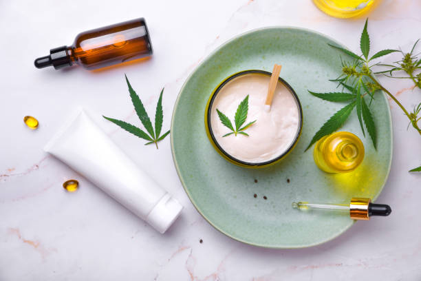 Cosmetics with cannabis oil on a turquoise plate on a light marble background.  Concept of luxury skin care.