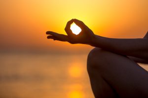 40670511 - young woman fingers in yogic jnana mudra, close up, copy space. relaxation, meditation on sea at sunset or sunrise
